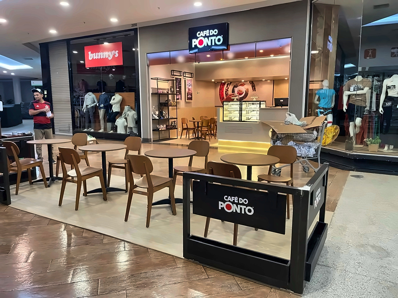 Fachada do Café do Ponto em shopping, com deck e mesas de madeira