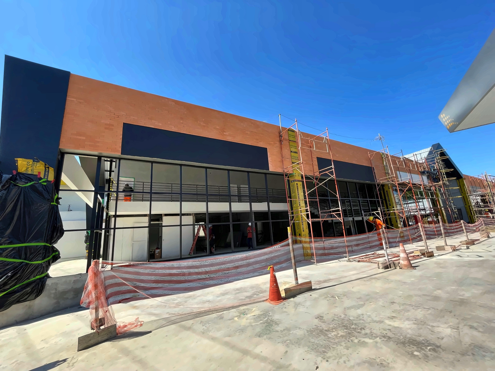 Fachada de edificação em obra, com andaimes e área isolada