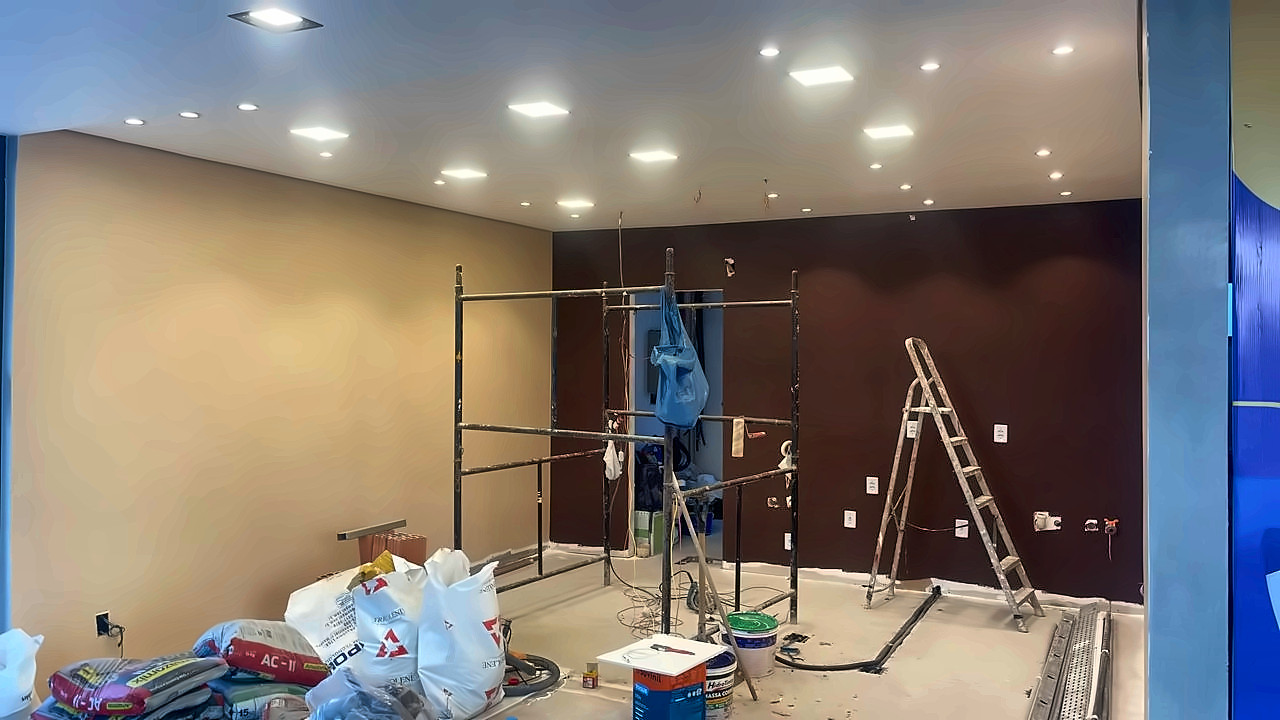 Loja em obra com paredes recém-pintadas, forro com iluminação embutida e andaime montado
